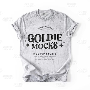 Peut inclure: Une maquette de t-shirt gris avec un aspect vieilli. Le texte "Real POD Mockup Photography" et "Goldie Mocks" est imprimé sur le t-shirt. Le texte "Mockup Studio" est imprimé sous le logo. Le texte "All of our images are real photographs of real POD products. We do not use any AI in our shop." est imprimé sous le nom du studio.