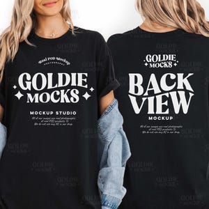 Peut inclure: T-shirt noir avec le texte "GOLDIE MOCKS" en blanc, dans une police stylisée. Le devant du t-shirt comprend également le texte "MOCKUP STUDIO". Le dos du t-shirt affiche "BACK VIEW MOCKUP".