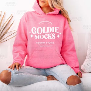 Puede incluir: Una sudadera con capucha rosa con un logotipo blanco que dice "Goldie Mocks Mockup Studio".