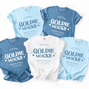 Peut inclure: Cinq t-shirts de différentes nuances de bleu et de blanc sont présentés. Chaque chemise affiche le texte "GOLDIE MOCKS MOCKUP STUDIO" dans une police stylisée. Les chemises sont disposées sur un fond blanc, mettant en valeur le design.