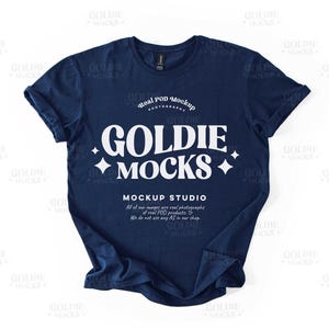 May include: A navy blue t-shirt mockup featuring the text "Goldie + Mocks" and "Real POD Mockup Photography" in white. The text "Mockup Studio" is also included with a description of the company's products.