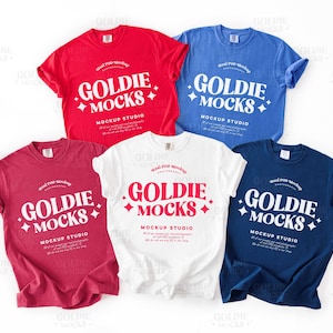 May include: Five t-shirts in different colors, red, blue, white, and two shades of red, with the text "Goldie Mocks Mockup Studio" printed on each.