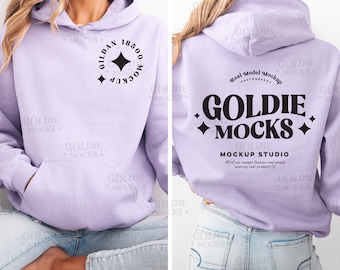 May include: A lavender hoodie with a black circle graphic on the left side and the text "GOLDIE MOCKS" on the back. The text is in a bold, retro font with a diamond design on either side. The text "MOCKUP STUDIO" is below the main text, and the text "All of our images feature real people wearing real products" is below that.