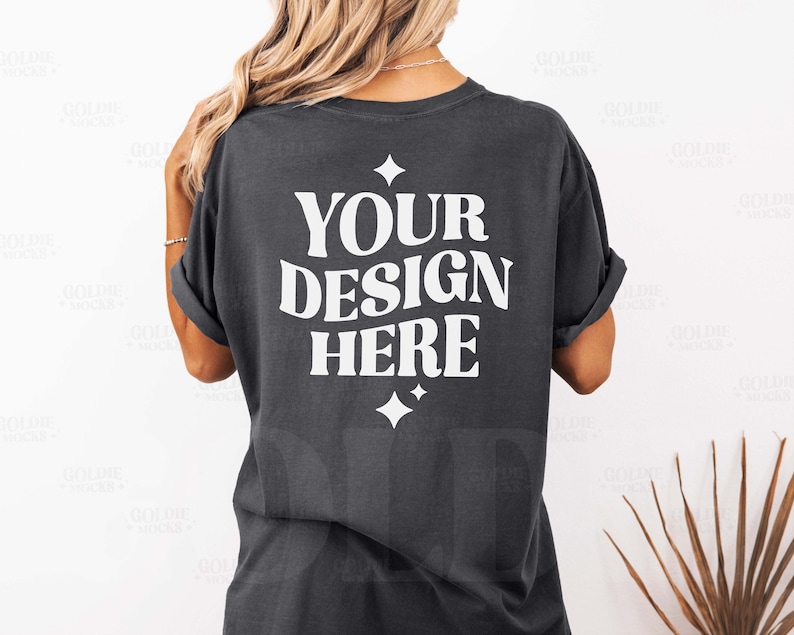K&ouml;nnte beinhalten: Ein dunkelgraues T-Shirt mit dem Text "YOUR DESIGN HERE" in Wei&szlig;. Das Shirt hat eine lockere Passform und ist aus einem weichen, bequemen Stoff.