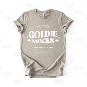 May include: A light brown t-shirt with a white graphic that says "GOLDIE MOCKS MOCKUP STUDIO".