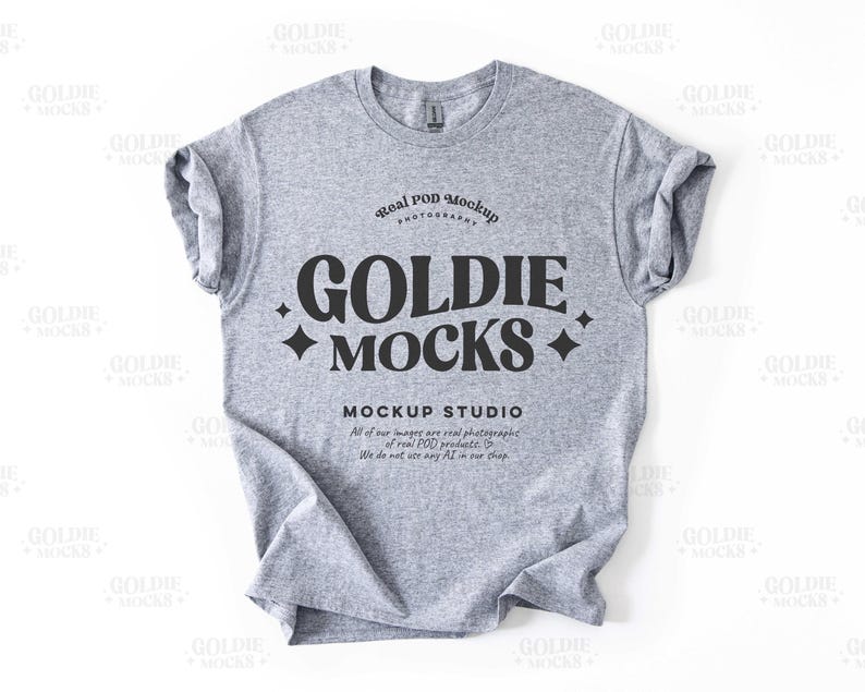 May include: A gray t-shirt mockup with the text "Goldie Mocks" in black lettering. The text "Real POD Mockup Photography" and "Mockup Studio" are also included in smaller font sizes.