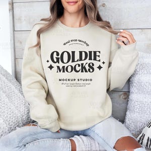 May include: A beige sweatshirt with the text "Real POD Mockup Photography Goldie Mocks + Mockup Studio All of our images feature real people wearing real products." printed on the front.