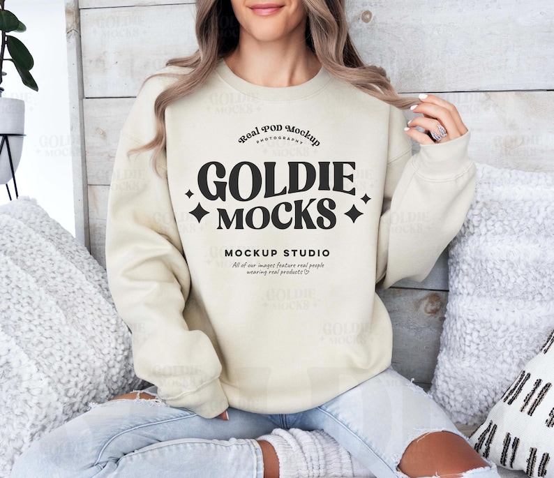 May include: A beige sweatshirt with the text "Real POD Mockup Photography Goldie Mocks + Mockup Studio All of our images feature real people wearing real products." printed on the front.