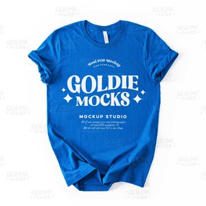Puede incluir: Una camiseta azul brillante de manga corta con un gráfico blanco que dice "Goldie Mocks" con el texto "Real POD Mockup Photography" y "Mockup Studio" debajo. El texto también dice "All of our images are real photographs of real POD products. We do not use any AI in our shop."