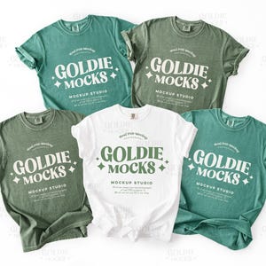 May include: Five t-shirts in various shades of green and white are displayed. Each shirt features the text "GOLDIE MOCKS MOCKUP STUDIO" in a stylized font. The shirts are arranged on a white background.