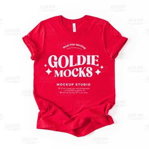 以下が含まれることがあります： 白い文字で「Goldie Mocks」と「Mockup Studio」と書かれた赤いTシャツのモックアップ。「Real POD Mockup Photography」という文字も見えます。