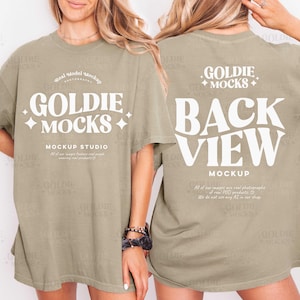 Puede incluir: Dos camisetas verde oliva. La parte delantera de la camiseta muestra el texto "GOLDIE MOCKS" en una fuente blanca estilizada. La parte trasera de la camiseta presenta las palabras "BACK VIEW" en una fuente blanca grande, con "MOCKUP" debajo.