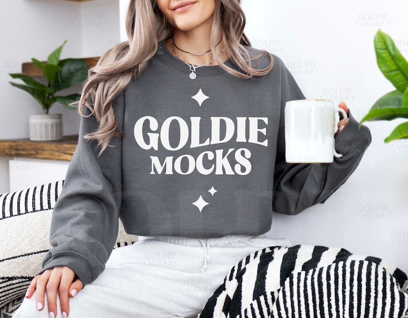 May include: A charcoal grey sweatshirt with the text "Goldie Mocks" in white lettering. The sweatshirt has a relaxed fit and a crew neckline.