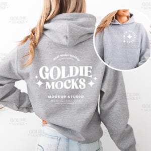 May include: A grey hooded sweatshirt with a white design on the back that says "Goldie Mocks Mockup Studio" and a white design on the front that says "Your Design Here".