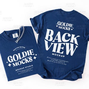 May include: Two navy blue t-shirts with white text and a silver chain necklace. One shirt displays "GOLDIE MOCKS" and "MOCKUP STUDIO". The other shirt shows "GOLDIE MOCKS" and "BACK VIEW MOCKUP".
