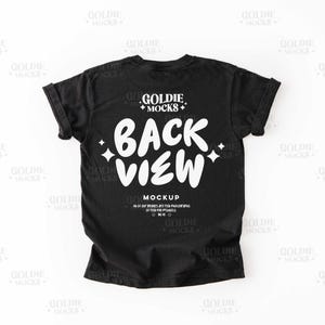 Pode incluir: Mockup de camiseta preta com mangas enroladas. A parte de trás da camiseta apresenta o texto "BACK VIEW" em uma fonte branca e em negrito, com o nome da marca "GOLDIE MOCKS" acima. A camiseta é exibida em um fundo branco.