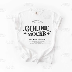 Może przedstawiać: Biała koszulka mockupowa z tekstem "Goldie Mocks" i "Mockup Studio" w kolorze czarnym. Tekst jest w retro stylu czcionki z diamentowym wzorem.