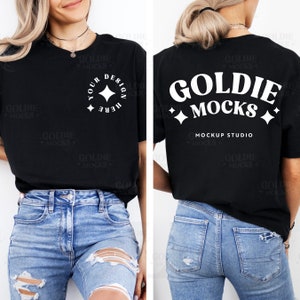 以下が含まれることがあります： 前面に白いデザイン、背面に「GOLDIE MOCKS MOCKUP STUDIO」というテキストが書かれた黒いTシャツ。青いジーンズを履いた人が着用しています。