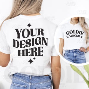 Op de afbeelding: Witte T-shirt mockup met de tekst "YOUR DESIGN HERE" gedrukt op de achterkant. Het shirt wordt gemodelleerd door een persoon die blauwe jeans draagt. De voorkant van het shirt heeft de tekst "GOLDIE MOCKS" erop gedrukt.