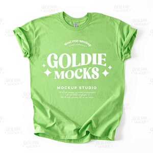 Puede incluir: Una camiseta verde brillante con un gráfico blanco que dice "Goldie Mocks" y "Mockup Studio".