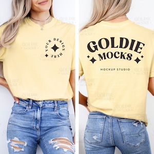 May include: A yellow t-shirt with a black design on the front that says "Your Design Here" with a star. The back of the shirt has a black design that says "Goldie Mocks" with stars and the text "Mockup Studio". The shirt is being modeled by a person wearing blue jeans.