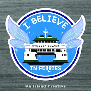 Op de afbeelding: Een ronde blauwe en witte sticker met een veerboot en feeënvleugels. De tekst "I Believe in Ferries" staat op de sticker. De veerboot heeft de tekst "Whidbey Island" aan de zijkant.