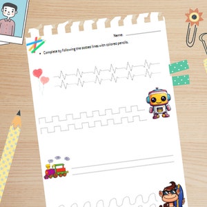 May include: A white educational worksheet with a spiral-bound top edge featuring dotted line tracing exercises. The page includes illustrations of two pink heart balloons, a small robot, a colorful train, and a monkey wearing sunglasses.
