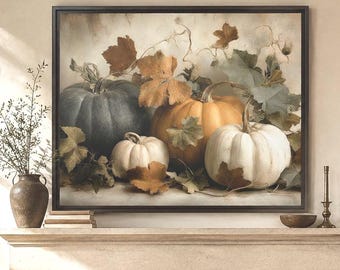 May include: A rectangular wall art print featuring a still life composition of pumpkins in shades of blue, orange, and white, surrounded by dried autumn leaves. The artwork is enclosed in a thin black frame and displayed above a stone fireplace.