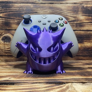 May include: A purple 3D printed Gengar Pokemon figure holding a white Xbox controller.