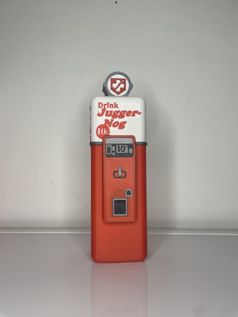 May include: A red and white vintage-style vending machine with the text "Drink Jugger-Nog 10&cent;" on the front. The machine has a small red cross on the top and a slot for coins.