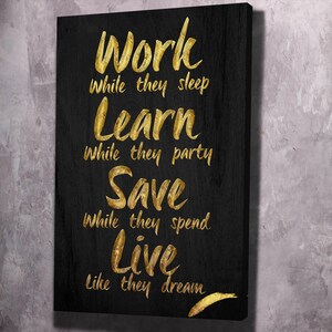 May include: Black canvas with gold lettering that reads "Work while they sleep, Learn while they party, Save while they spend, Live like they dream."