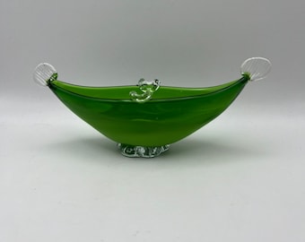 May include: A green glass bowl shaped like a canoe with clear glass handles. The bowl has a rounded base.