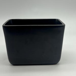 Puede incluir: Un macetero rectangular de cerámica negra con bordes redondeados.