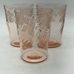 Könnte beinhalten: Set aus drei rosa Glasbechern mit einem Spiraldesign und einem geätzten Weinstockmuster.