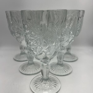 May include: Set of six clear glass wine goblets with a cut glass design. The goblets have a round bowl and a tall stem with a flared base.