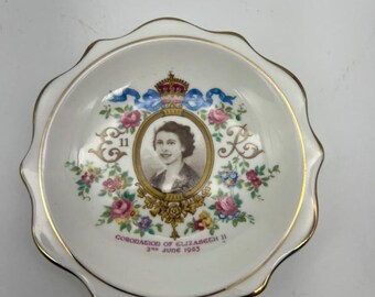 Pode incluir: Um prato de cerâmica branca com borda dourada e design floral. No centro, um retrato da Rainha Elizabeth II com o texto "Coronation of Elizabeth II 2nd June 1953".