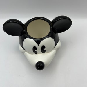 Peut inclure: Pot en c&eacute;ramique noir et blanc en forme de t&ecirc;te de Mickey Mouse. Le pot a une ouverture ronde en haut pour la plantation.