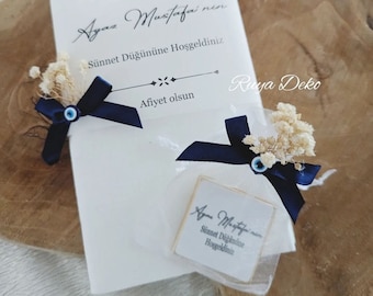 May include: A white card with blue ribbon and a blue evil eye charm. The card has the text "Ayaz Mustafa nen Sünnet Düğününe Hoşgeldiniz Afiyet olsun Ruya Deko" printed on it.