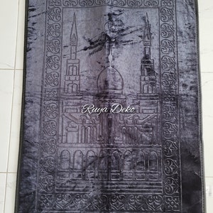 May include: A black prayer rug with a detailed embroidered design of a mosque and crescent moon. The rug has a fringe border and the text "Ruyya Deko" is embroidered in the center.