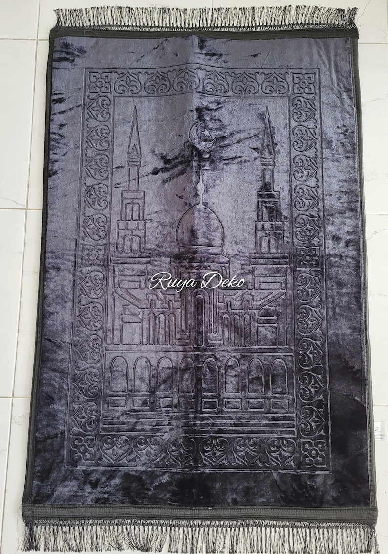 May include: A black prayer rug with a detailed embroidered design of a mosque and crescent moon. The rug has a fringe border and the text "Ruyya Deko" is embroidered in the center.