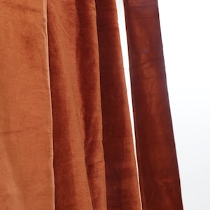 May include: Close-up of a set of brown velvet curtains hanging from a metal rod.