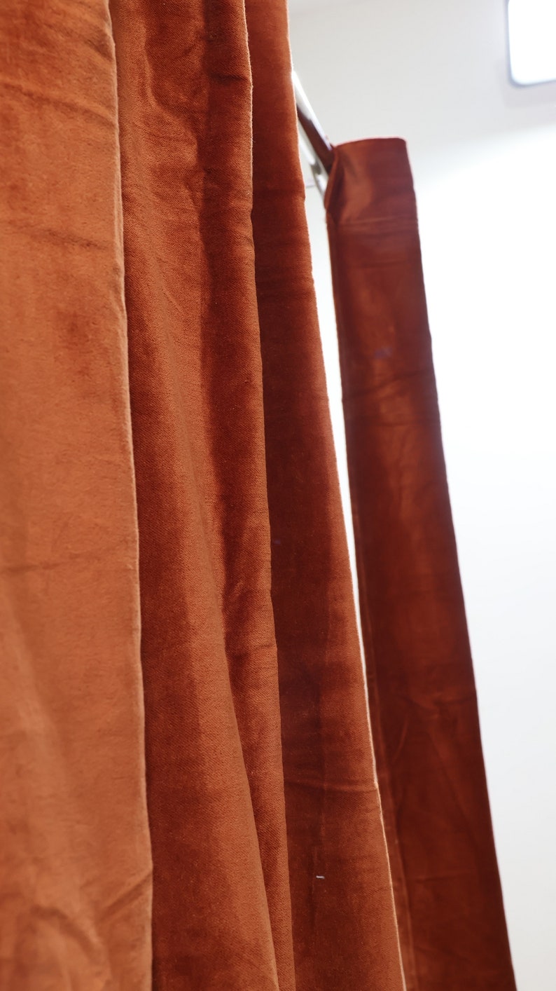 May include: Close-up of a set of brown velvet curtains hanging from a metal rod.