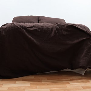 May include: A dark brown linen duvet cover is neatly arranged on a bed with two matching pillowcases. The duvet cover is smooth and wrinkle-free, showcasing the natural texture of the linen fabric.