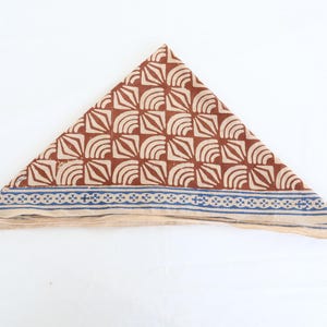Może przedstawiać: Brązowo-biała bawełniana bandana z niebieskim wykończeniem. Bandana jest złożona w kształt tr&oacute;jkąta.