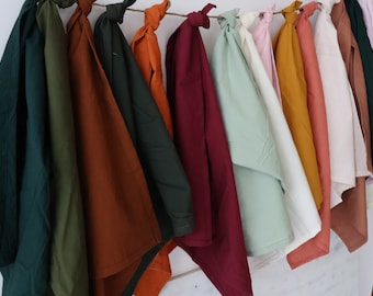 May include: A collection of 12 fabric swatches in various colors, including green, brown, red, and white. The swatches are hung on a string and are arranged in a row.