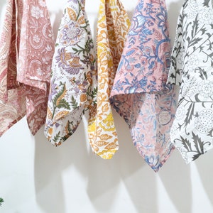 Puede incluir: Seis toallas de cocina con diferentes patrones colgadas en una pared blanca. Las toallas son de algod&oacute;n y presentan dise&ntilde;os florales en tonos rosa, azul, amarillo y blanco.
