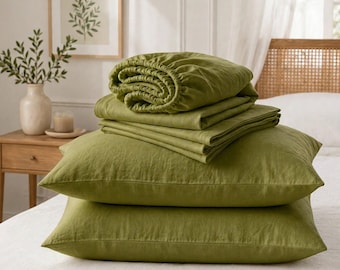 May include: A set of olive green bedding featuring two rectangular pillowcases stacked at the bottom, topped with a folded flat sheet and a fitted sheet with elasticized edges. The fabric has a visible, textured weave throughout the entire set.