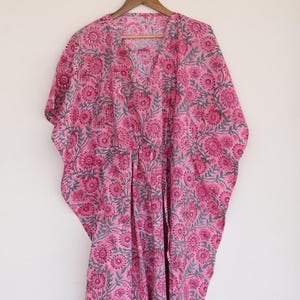 May include: A pink and gray floral print kaftan with a V-neck and short sleeves.