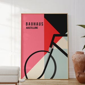 Könnte beinhalten: Ein Poster mit einem geometrischen Design, das ein Fahrrad in Schwarz, Rot, Weiß und Blau zeigt. Das Poster trägt den Text "Bauhaus Ausstellung" in Schwarz.