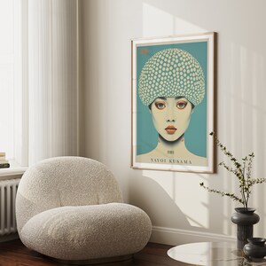 May include: A framed art print depicting a woman with a polka-dot hat. The artwork has a teal background and a light wood frame. The text "Yayoi Kusama" is visible.